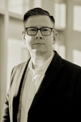 Profile portrait of a man in a white shirt against a light background
